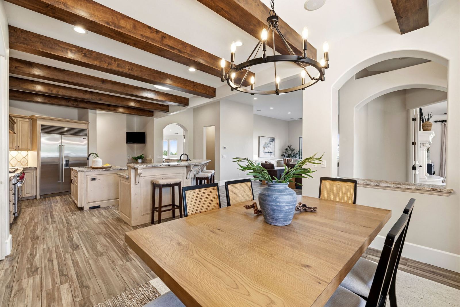 Dining table beside the kitchen under an iron chandelier