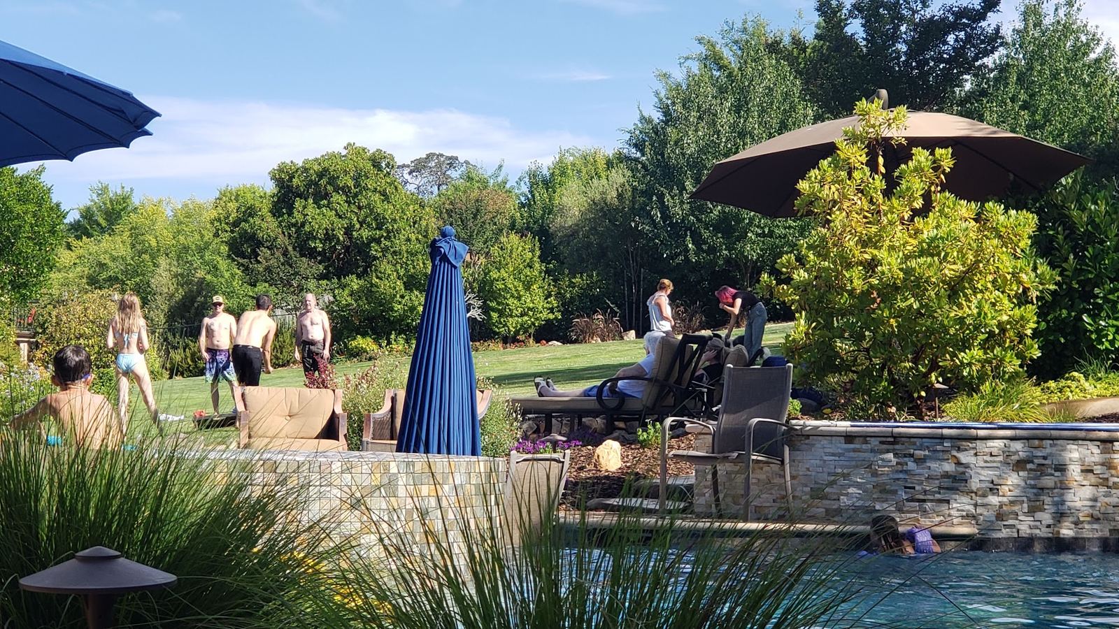 Guests playing lawn games beyond the pool