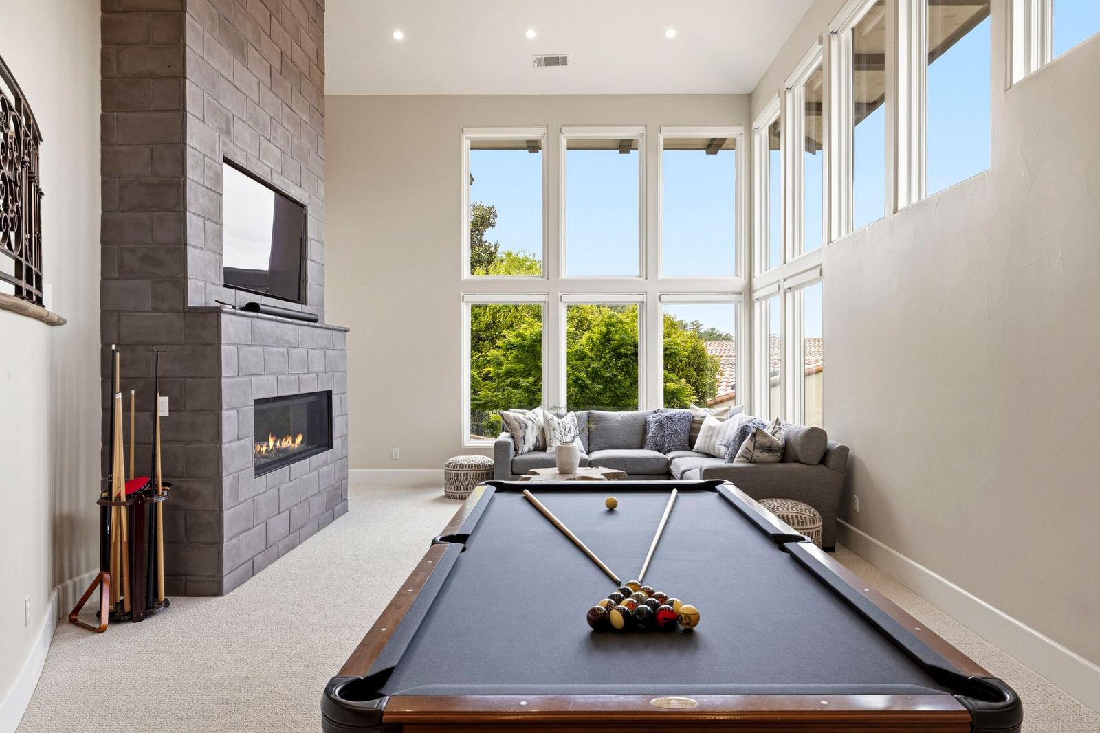 Two-story media and game lounge with billiards table and linear fireplace